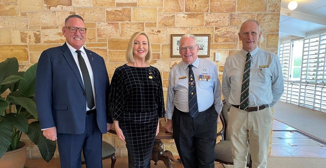 Three men and a woman posing for camera in front of a sandstone interior wall