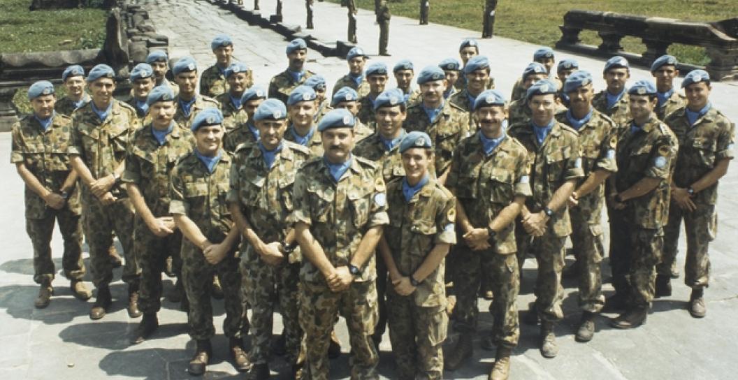 Soldiers wearing blue caps standing in formation in front of temple complex