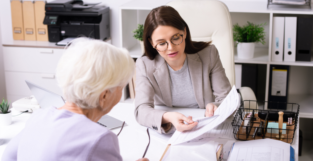 Younger woman explaining a document to an older woman