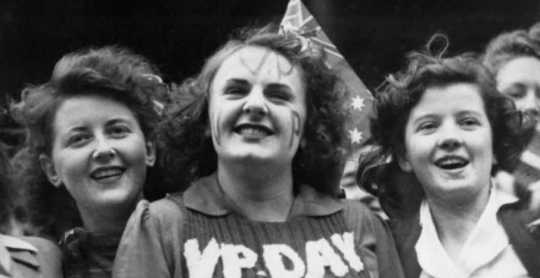 Three young women smiling, one with VP Day written on her jumper
