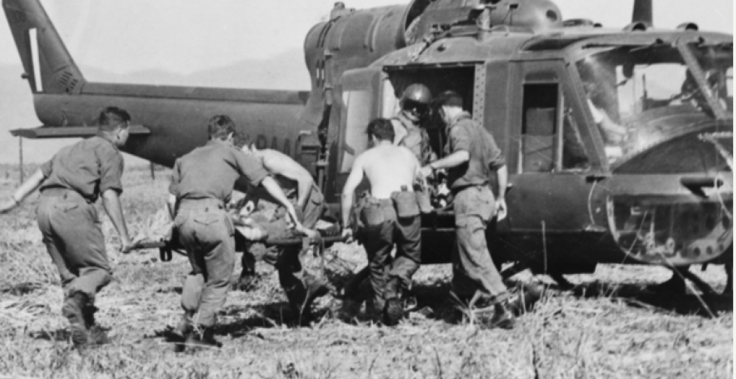Five soldiers help get a man on a stretcher aboard a helicopter