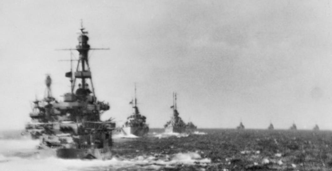 Warships in foreground with four other ships on the horizon