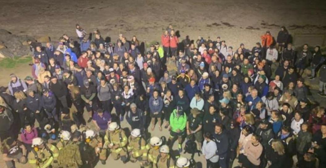 Crowd of about 100 people gathered on beach at night.