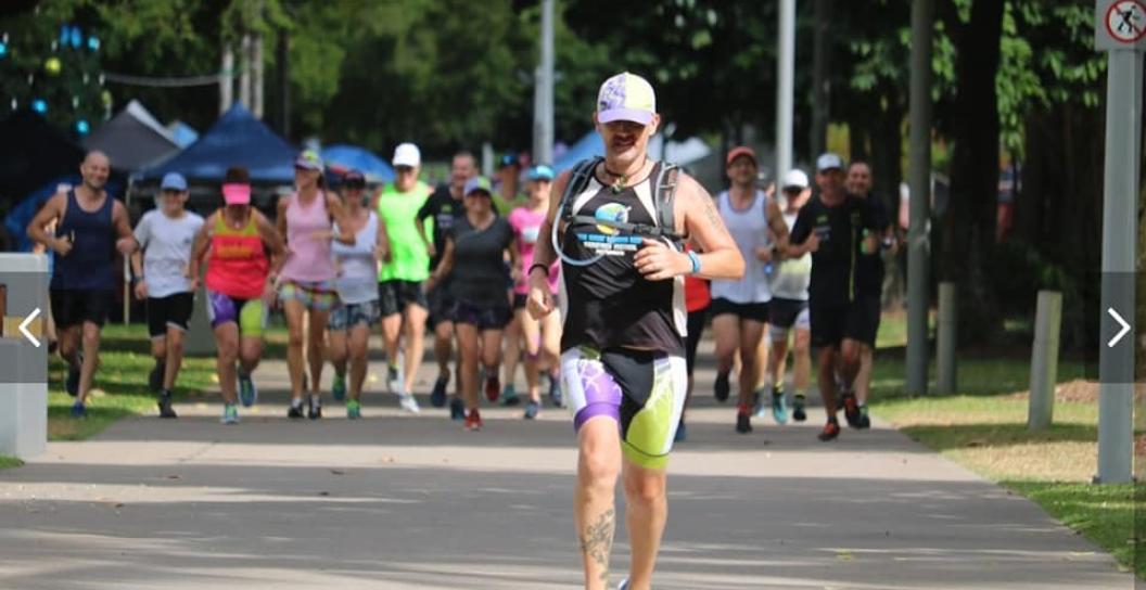 Man running towards camera with 20 or so people in group behind him