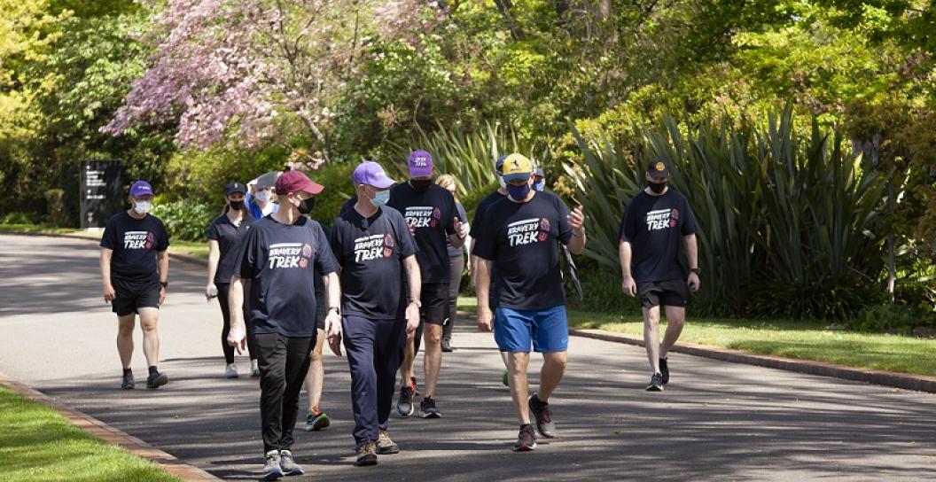 Several men wearing Open Arms T-shirts walking down a path in what looks like a park