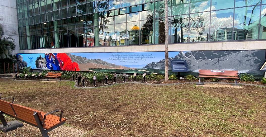 A remembrance garden under construction with a modern office block behind it