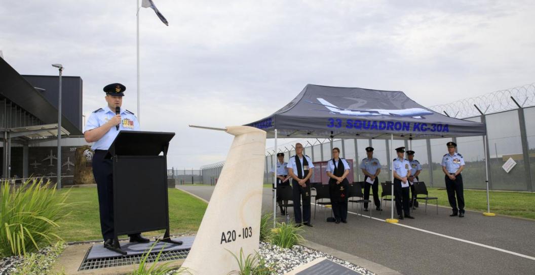 RAAF officer gives speech next to marquee with more RAAF personnel inside