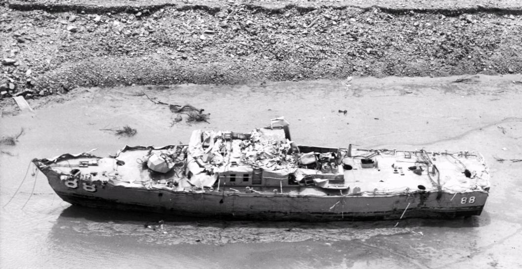 A badly damaged patrol ship in the shallows of a beach
