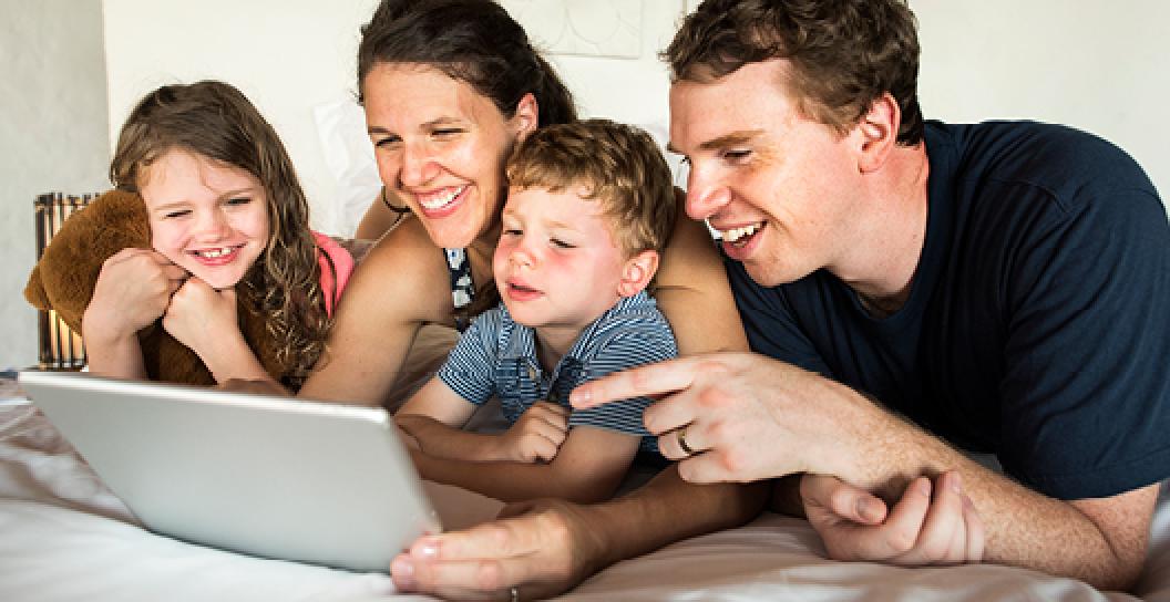 Family of 4 smiling at a computer screen