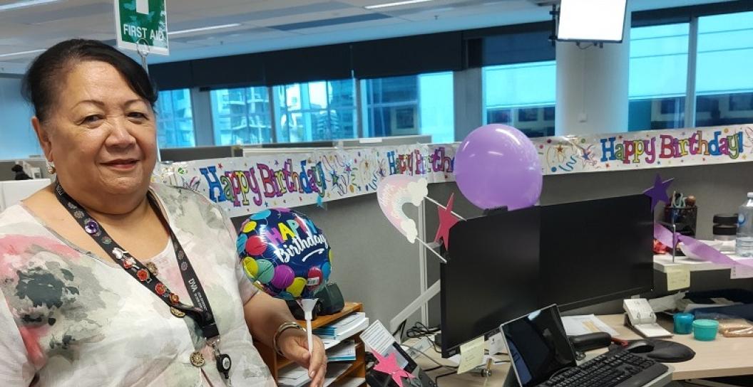 Smiling woman standing next to desk covered in farewell messaging