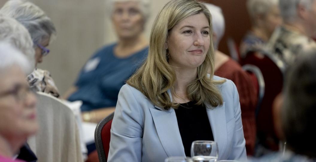 Smiling woman sitting at dinner table at dinner event