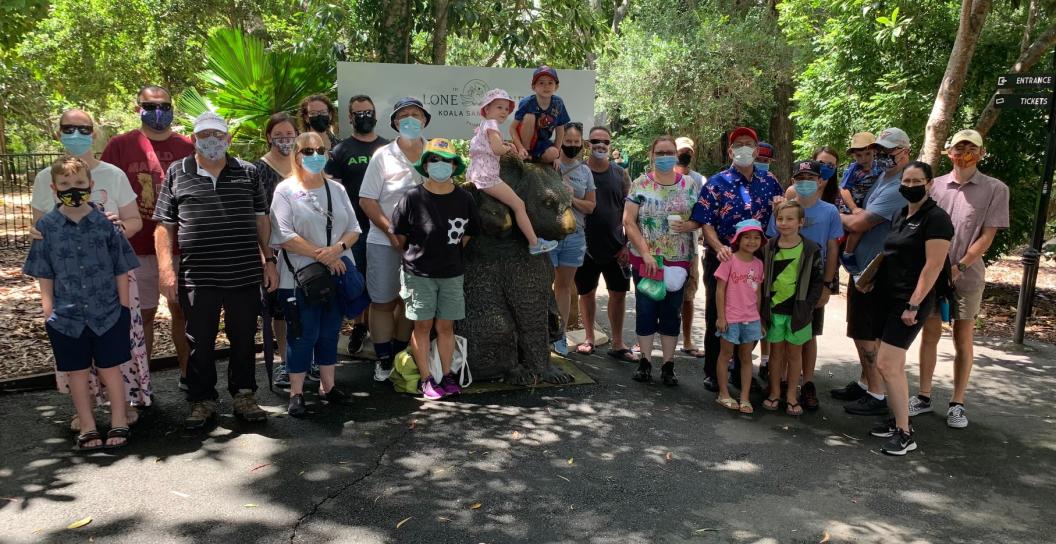 Group of 20 or so people of various ages pose for photo in bush setting