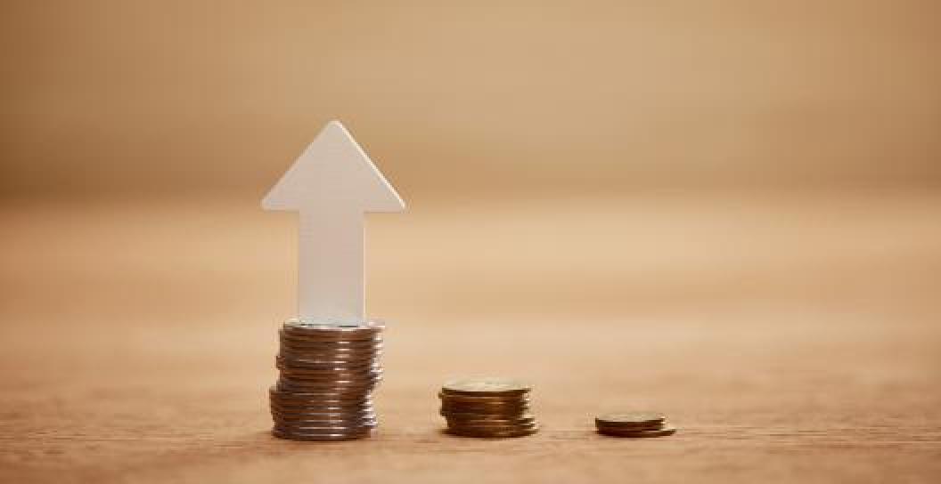 Stock photo showing stack of coins with upward facing arrow on one of them