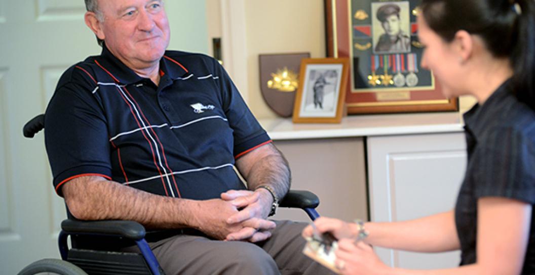 A male veteran aged around 70 years old is sitting in a wheelchair and talking with an occupational therapist