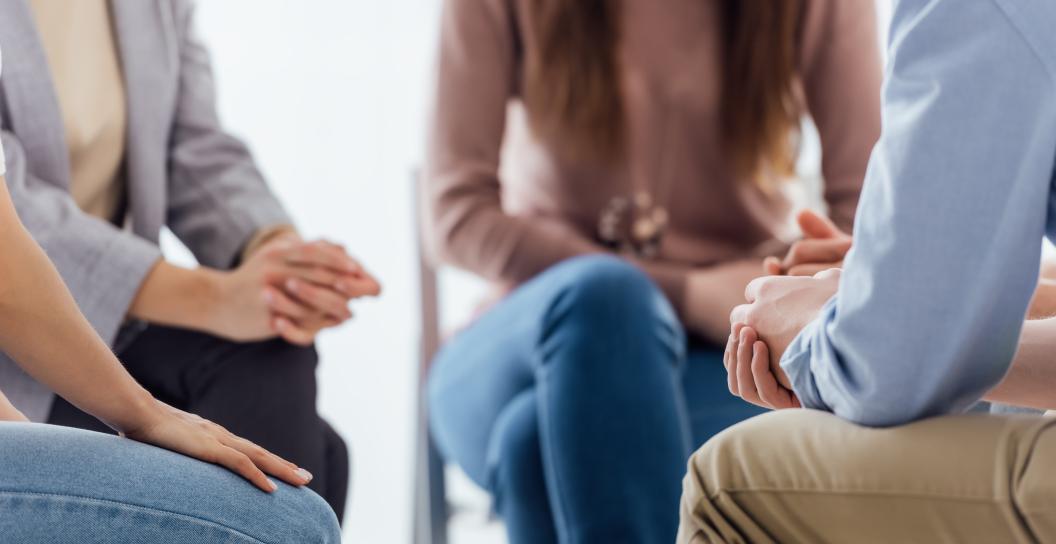 A close up photo of four people sitting in a circle on chairs