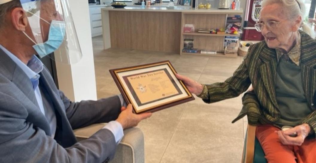 Man in face mask hands certificate to elderly woman