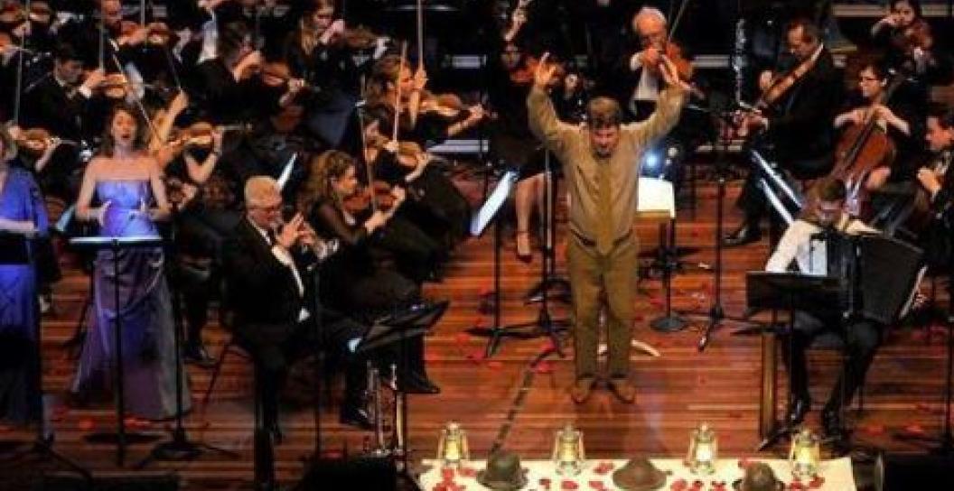 Conductor in khaki surrounded by an orchestra