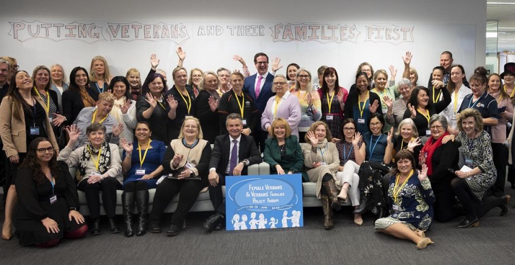 Group of about 40 women and three men posing for camera in office