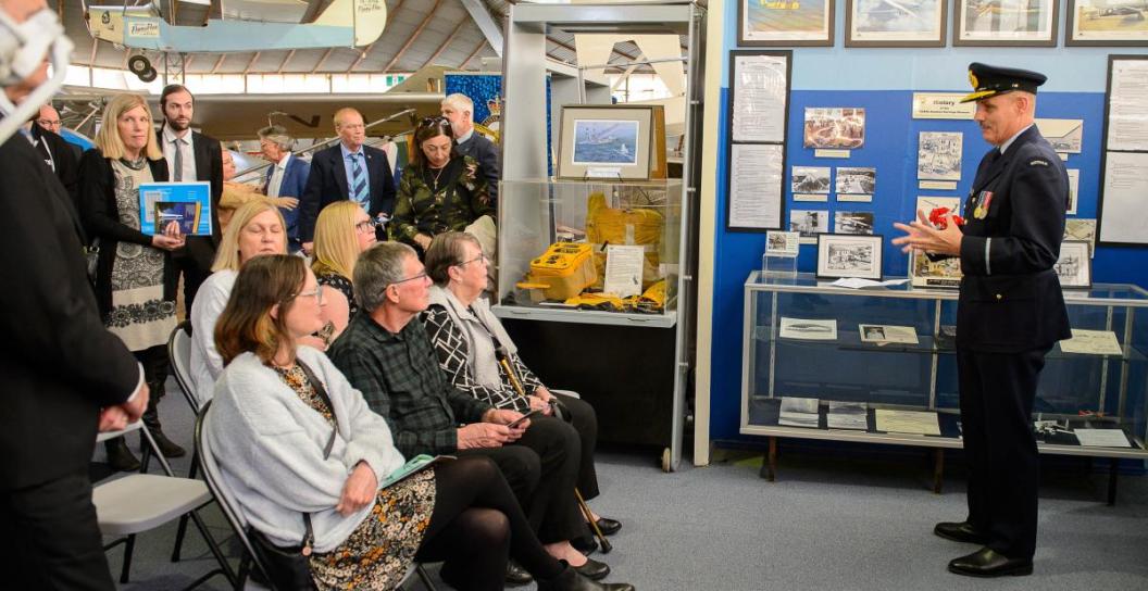 Air Commodore addresses about a dozen people in an aircraft museum