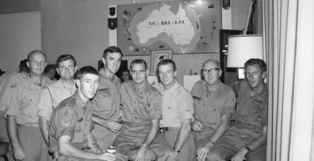 Black and white photo of eight men in uniform posing for camera