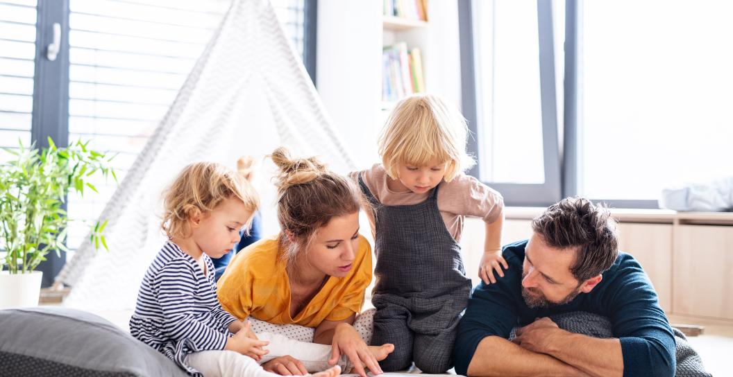 Young family with two children reading a book on the floor