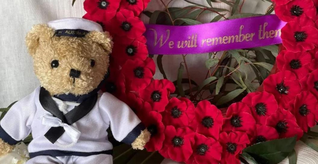 Teddy bear in sailor uniform next to wreath