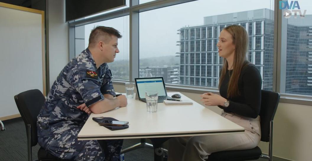 Young man in RAAF uniform talks to young female civilian in office