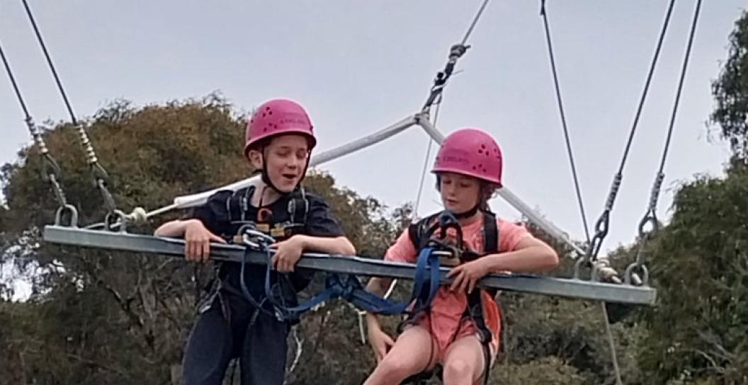Two female children are climbing on an obstacle course