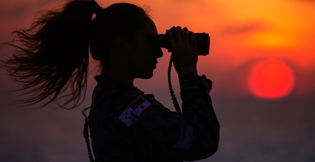 Royal Australian Navy Able Seaman Hydrographic Survey Operator Jessica Cafagna keeps a look out from HMAS Leeuwin's flightdeck at sunrise