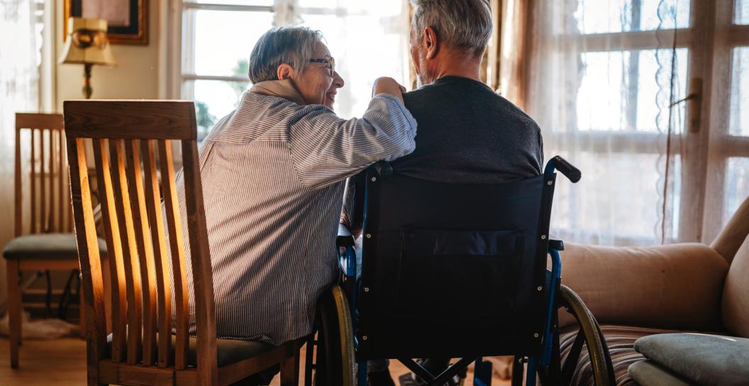 Senior couple sitting together - one person is in a wheelchair.