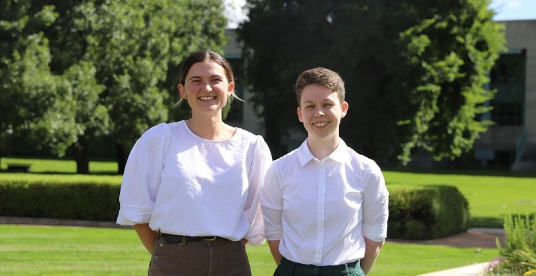 Two young women standing in pleasant grassy grounds