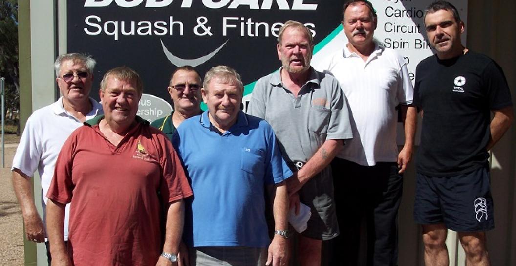 A group of overweight middle-aged men smiling at camera