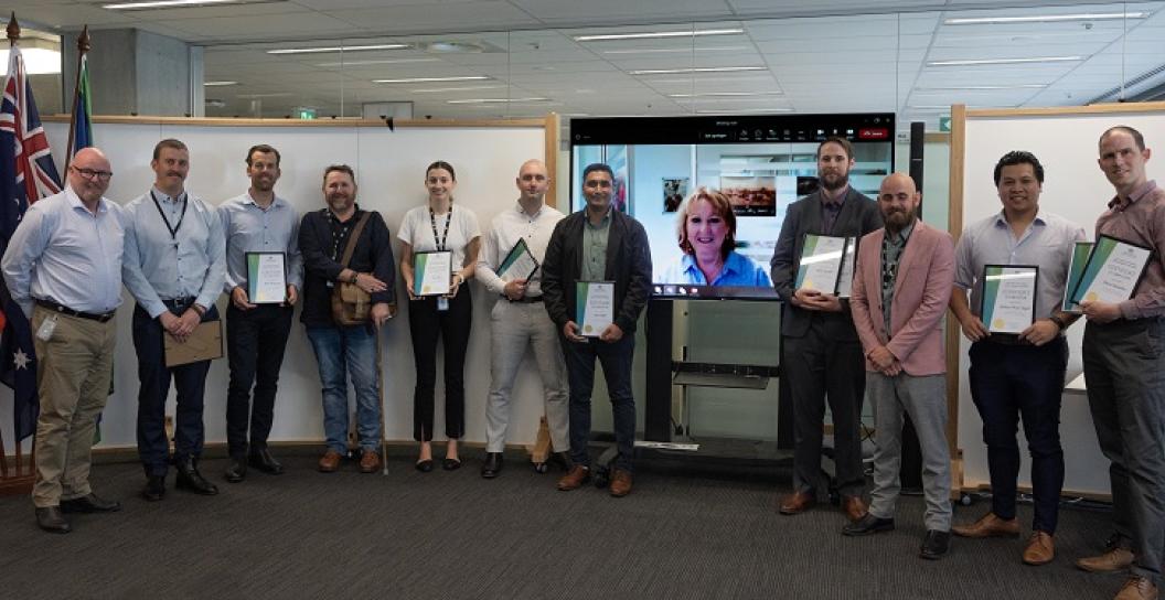 Twelve people pose for the camera in an open office area