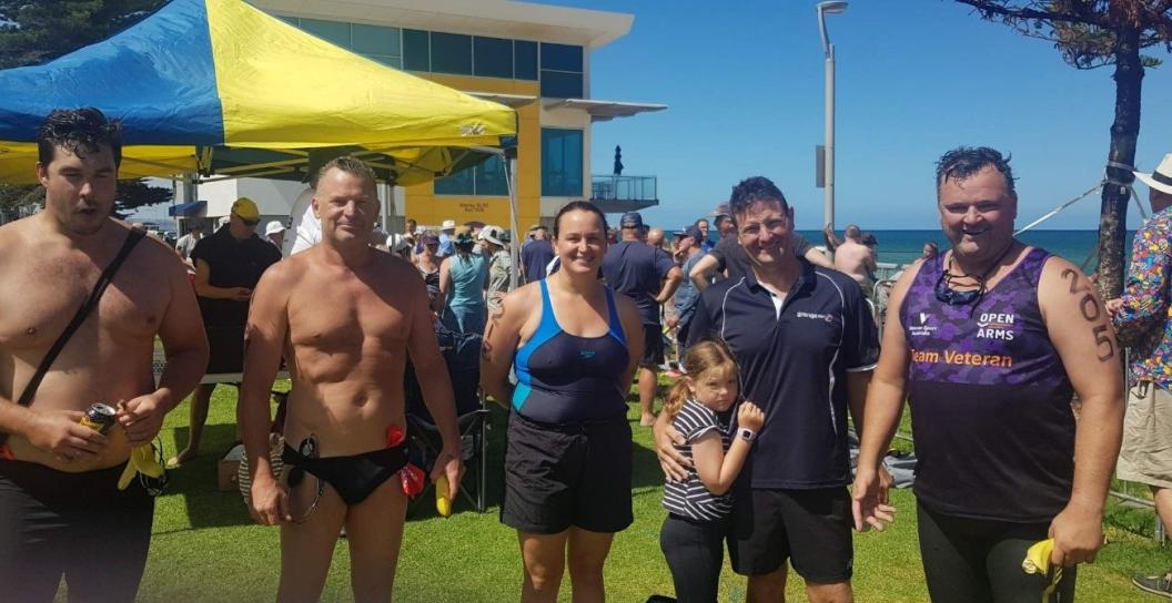 four men and a woman pose next to beach