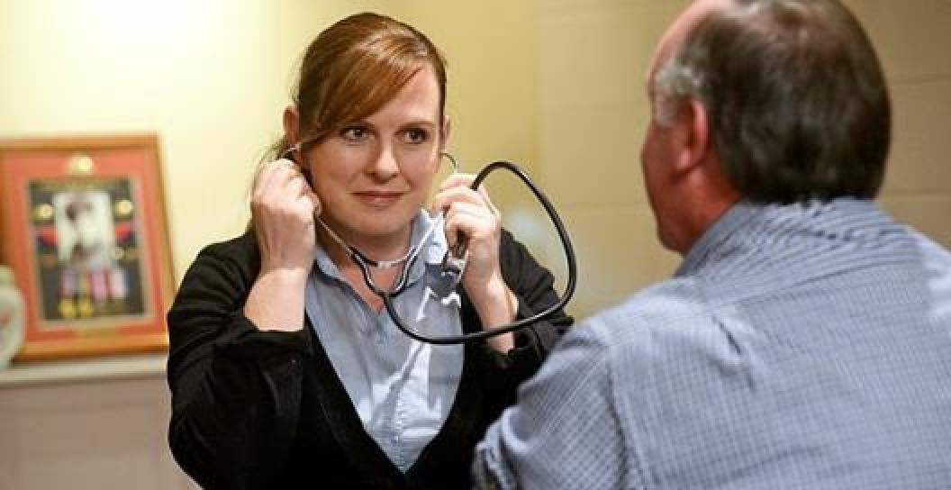 Nurse with stethoscope talking to older man
