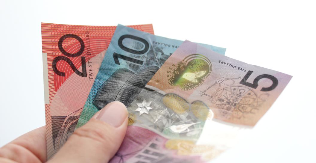 A hand holds Australian currency in 20, 10 and 5 dollar notes