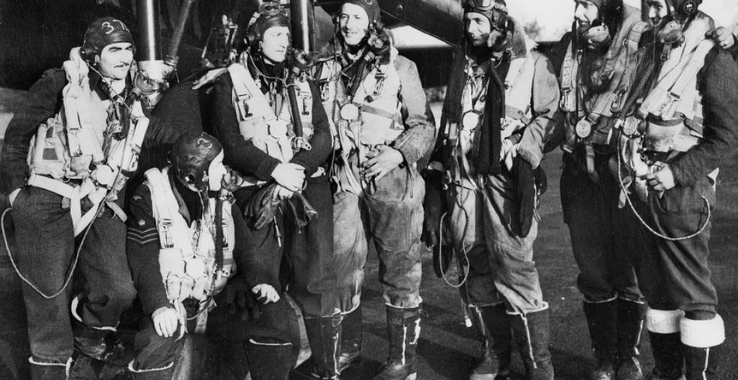 Six airman in flying gear pose next to aircraft