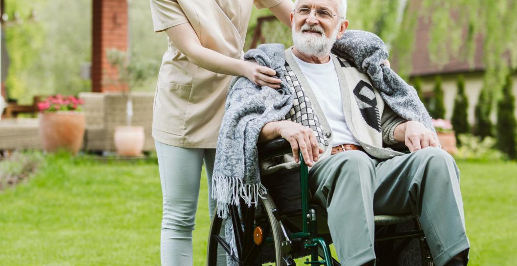 Care and support worker providing companionship for man in wheelchair.