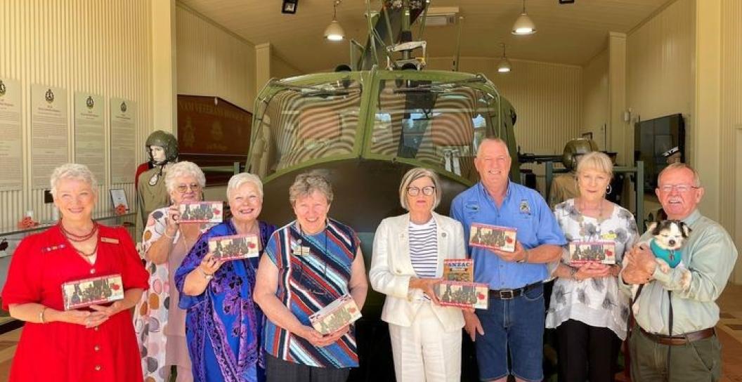 Group of eight people posing in front of Army helicopter in a museum