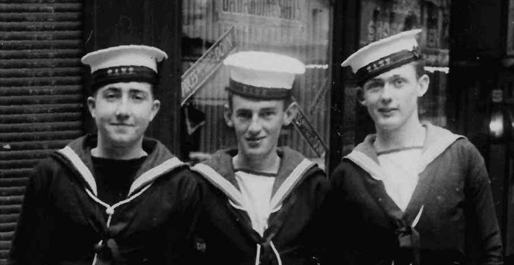 Black and white photo of three young sailors on city street