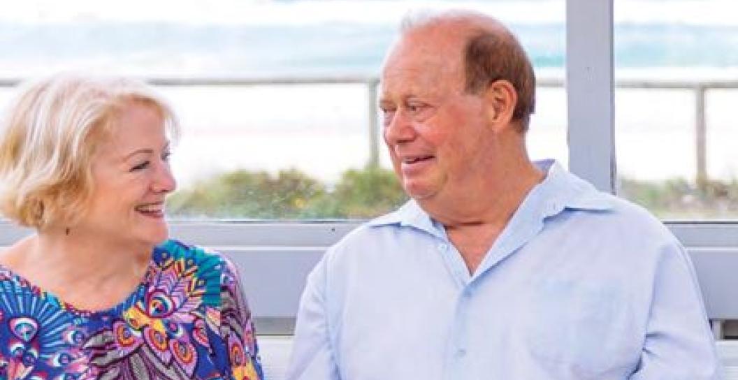 Two older people at bus stop with surf in background