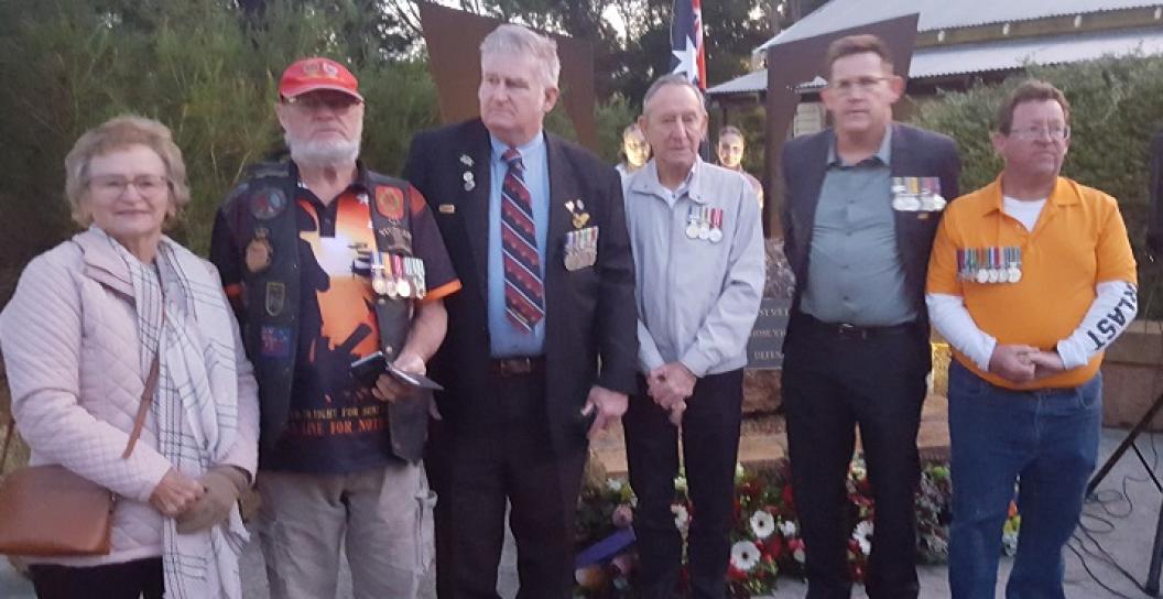Five older men and one older woman pose for photo. Most are wearing medals.
