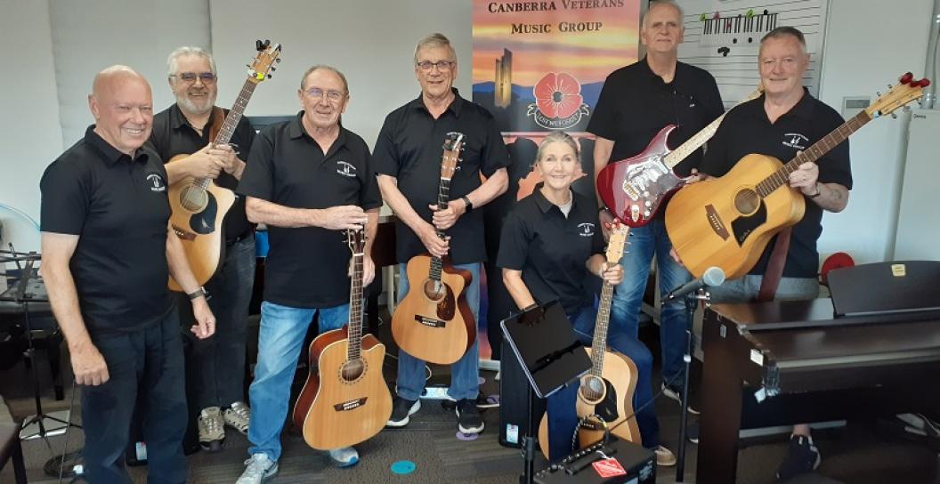 Seven people posing for camera holding guitars