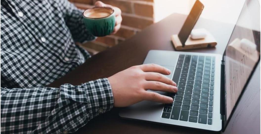 Man working at the laptop with a cup of coffee.