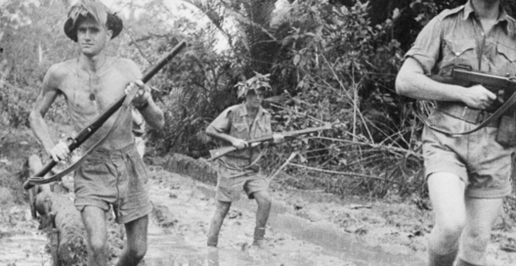 A black and white photo of Australian soldiers patrolling in the mud.