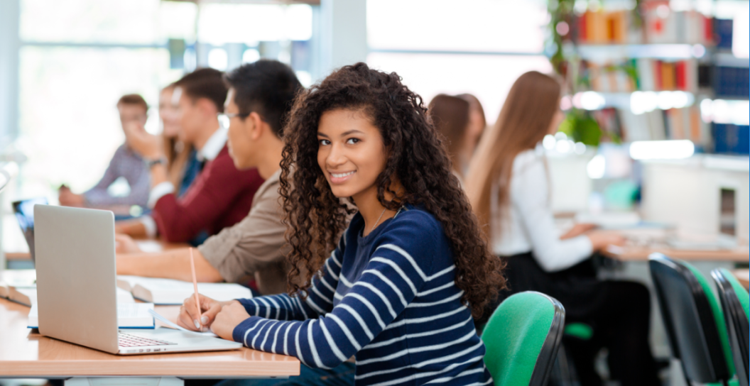 Student sitting at a desk with head turned to face the camera