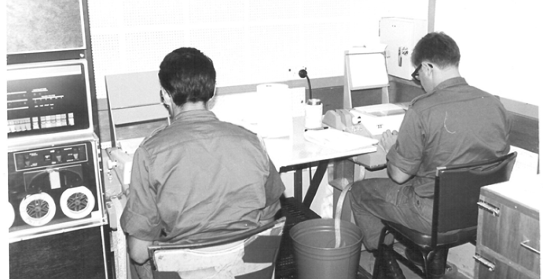 Two young men in uniform in front of teleprinters or similar.