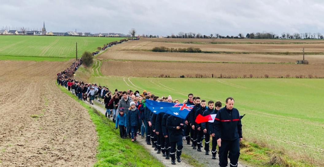 Hundreds of people walking down a road in the countryside.