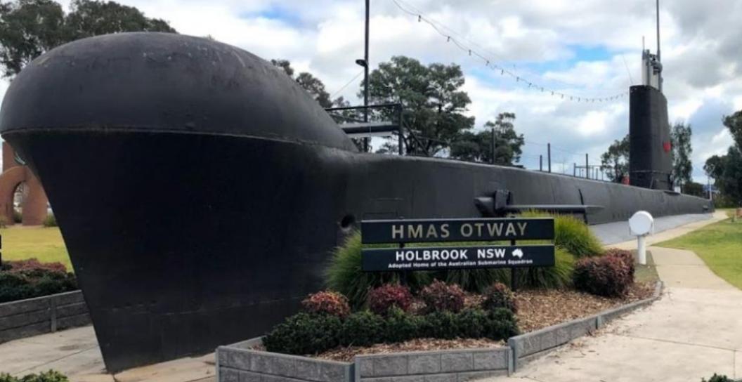 Photo of submarine in park with sign in front reading 'HMAS Otway Holbrook NSW'