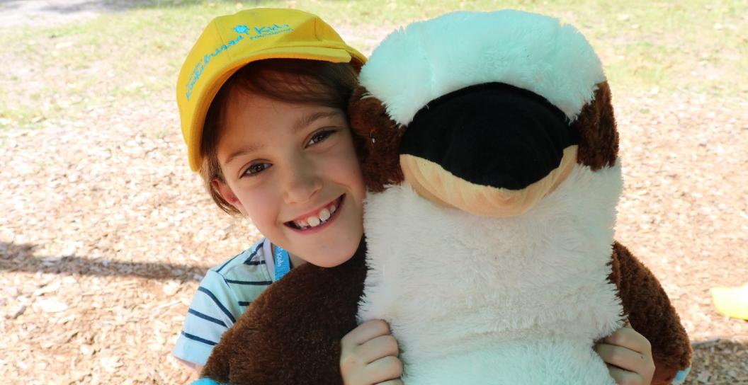 A child holding a kookaburra toy outside in the park